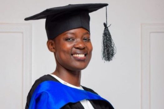 Smiling girl in university in cap and gown for graduation